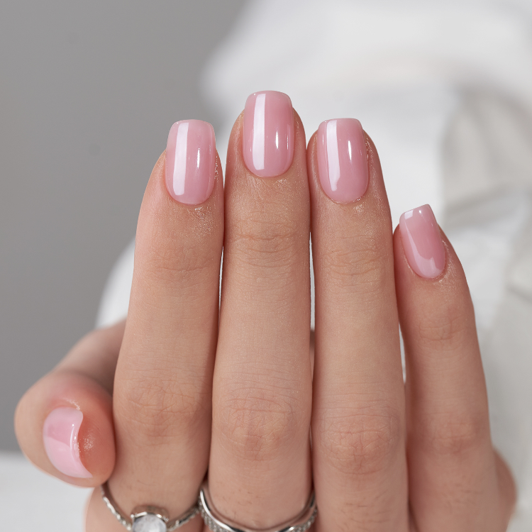 Model wearing soft pink short press on nails Australia with natural finish